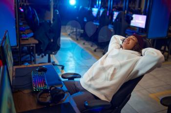 Young gamer resting in gaming armchair, game club. Virtual entertainment, e-sport tournament, cybersport lifestyle. Male person leisures in internet cafe