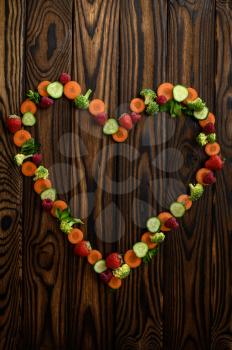 Vegetable heart on wooden background, top view. Organic vegetarian food, grocery assortment, natural eco products, healthy lifestyle concept