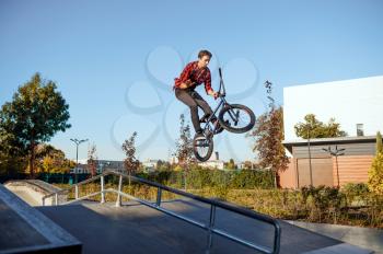 Male bmx biker, jump in action, teenager on training in skatepark. Extreme bicycle sport, dangerous cycle exercise, risk street riding, biking in summer park