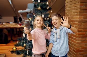 Children bloggers makes selfie at christmas tree. Kids blogging in home studio, social media for young audience, online internet broadcast