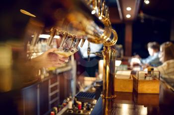 Bartender pours fresh beer into a glass. Friends leisures at the counter in bar, nightlife. Group of people relax in pub, night lifestyle, friendship, event celebration