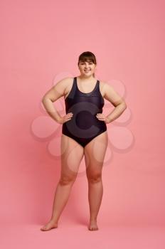 Overweight woman in swimsuit, body positive, pink background. Obesity fighting, cheerful female person without complexes, striving for a healthy lifestyle