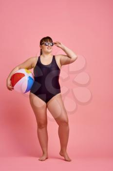 Overweight woman in swimsuit and sunglasses, body positive, pink background. Obesity fighting, cheerful female person without complexes, striving for a healthy lifestyle