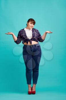 Cute overweight woman in studio, body positive, blue background. Obesity fighting, cheerful female person without complexes