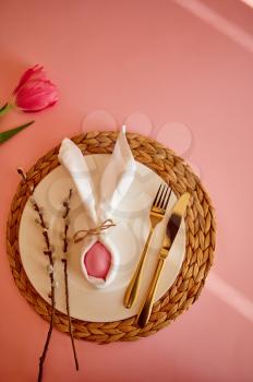 Blooming tulip, easter egg on plate and tableware on pink background. Spring tree blossom and paschal food, fresh floral decoration for holiday celebration, event symbol