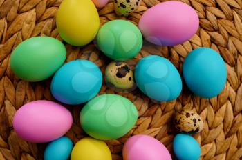 Colorful easter eggs on wicker wood background, closeup view. Paschal food, event decoration, spring holiday celebration symbol