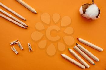 Pencils and paper clips on orange background. Office stationery supplies, school or education accessories, writing and drawing tools