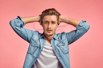 Stressed man portrait, pink background, emotion. Face expression, male person looking on camera in studio, emotional concept, feelings