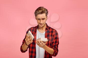 Surprised man opens gift box, pink background, emotion. Face expression, male person looking on camera in studio, emotional concept, feelings