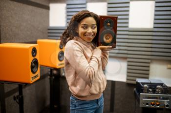 Smiling woman holds sound speaker in music store. Female person in audio shop, amplifier on background, buyer in multimedia salon