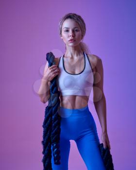 Young sportswoman with ropes poses in studio, neon background. Fitness woman at the photo shoot, sport concept, active lifestyle motivation