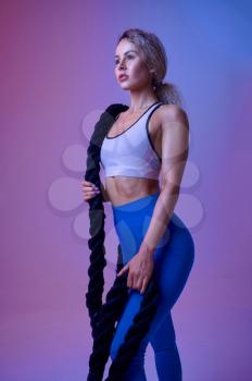 Young sportswoman with ropes poses in studio. Fitness woman at the photo shoot, sport concept, active lifestyle
