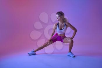 Sportswoman doing stretching exercise in studio, neon background. Fitness woman at the photo shoot, sport concept, active lifestyle motivation