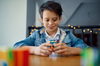 Little boy trying to solve puzzle cubes. Toy for brain and logical mind training, creative game, solving of complex problems