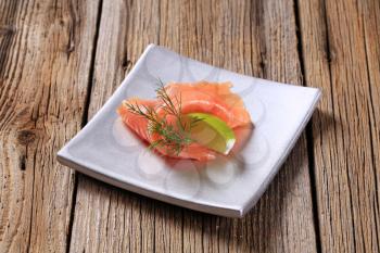 Thin slice of smoked salmon and wedge of  lime