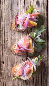 Salmon sandwiches garnished with salad greens and onion