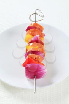 Slices of sausage, pepper and onion on a skewer