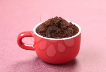 Heap of freshly ground coffee in a red cup
