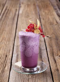 Glass of blueberry smoothie on wooden table