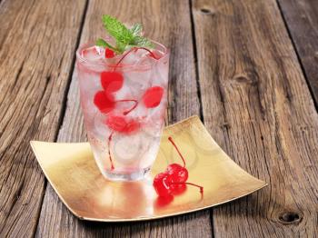 Glass of iced drink with maraschino cherries