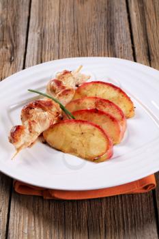 Chicken skewer and slices of baked apple 