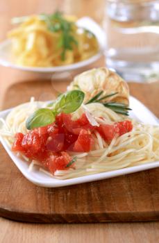 Spaghetti, peeled tomato and baked garlic - closeup