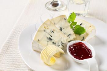 Wedges of blue cheese and fruit preserve on porcelain spoon