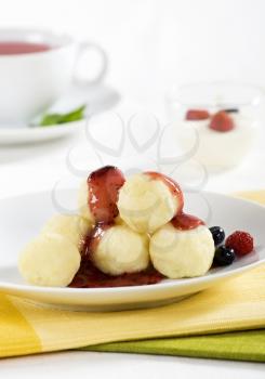 Fruit dumplings, bowl of creamy cheese and a cup of tea
