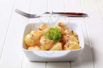 Cheese coated potatoes in porcelain dish