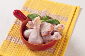 Raw chicken drumsticks in a pan