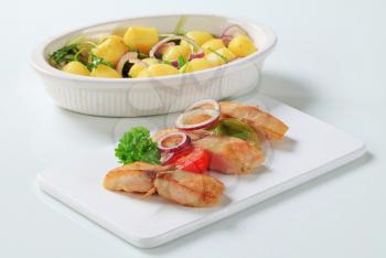 Fish skewer and potatoes in casserole dish
