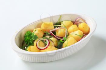 Potatoes with onion and arugula in casserole dish