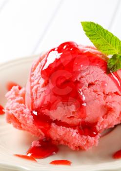 Scoop of pink ice cream with raspberry sauce