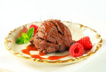 Scoop of chocolate ice cream with caramel sauce and raspberries