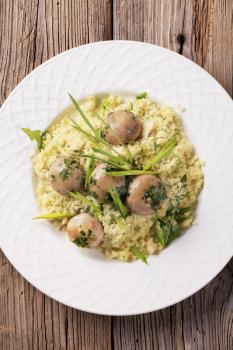Couscous with button mushrooms and pesto styled with spring onion