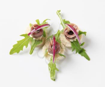 Anchovy canapes garnished with arugula and onion