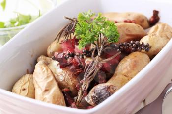 Baked potatoes and smoked meat in a casserole dish