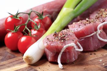 Raw pork tenderloin and vegetables on a cutting board