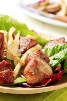 Pieces of pan roasted pork on lettuce leaves