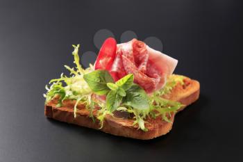 Slice of toasted bread with salami and ham