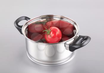 Stainless steel pot with a tomato in it