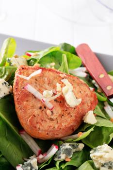 Marinated pork chop on bed of spinach salad