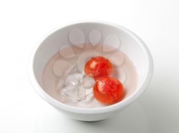Red tomatoes in cold water ready to be peeled