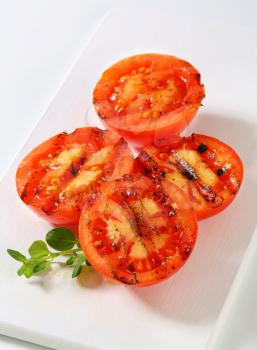 Grilled tomatoes on white cutting board