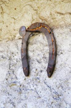 Rusty horseshoe hanging on a nail on a wall
