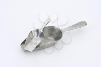 two empty metal scoops on white background