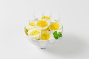 hard boiled egg halves in white bowl