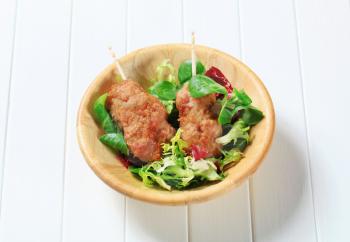 Rolled minced meat on stick served with green salad