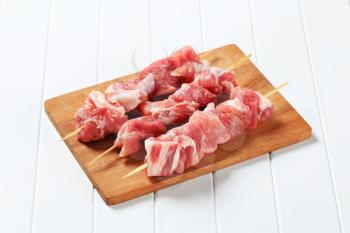 Raw pork skewers on cutting board