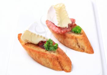 Crostini topped with white rind cheese and salami